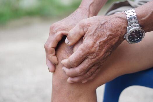 Close up elderly man hurt his knee, use hands to massage knee. Concept, health care and health problems. Artritis symptom. Suffering from knee pain. Tendon problems and Joint inflammation photo