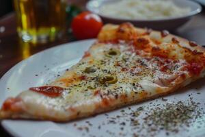 Delicious slice of pizza covered in melted mozzarella and spices on white plate photo