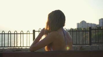 Girl on a bench is sad. View of the sea and sunset video