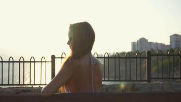 Girl on a bench is sad. View of the sea and sunset video