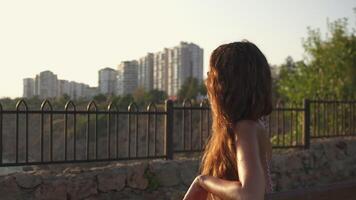 Girl on a bench, watching the sea and enjoying the sunset. video