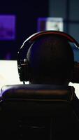 vertical homem jogando sf espaço videogame em pc tela dentro Sombrio quarto vestindo fones de ouvido, tiroteio asteróides. jogador desfrutando nave espacial vôo jogos em computador monitor, destruindo meteoritos, Câmera b video