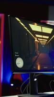 Vertical Panning shot of empty neon lit living room with RGB lit computer on table next to headphones and high tech VR headset. FPS videogame left open on pc display and computer peripherals in apartment video