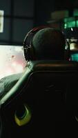 Vertical Pro gamer wearing headphones playing science fiction game. Content creator in gaming chair talking with audience on headset mic, filming tutorial on how to defeat enemies, camera B video