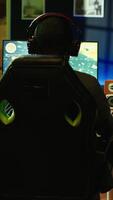 Vertical Man having fun playing videogames on desktop computer, chatting with teammates through headphones mic. Relaxed gamer communicating with friends through headset microphone during game at home, camera B video
