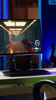 Vertical Neon lit components on opened gaming PC device next to keyboard, speakers, wired mouse and headphones in empty apartment. Computer in home with colorful gpu and cpu parts, panning shot video