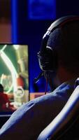 Vertical Player using keyboard, mouse and headset to play first person shooter videogame on PC, enjoying leisure time. Man in living room using high tech computer peripherals to destroy enemies, camera A video