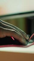 Vertical Gamer using keyboard and wired mouse to play videogames on desktop PC, close up shot. Man playing online game in front of monitor with computer peripherals at desk in apartment, camera A video