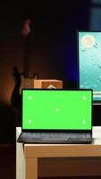 Vertical Mockup laptop on desk next to man playing SF videogame on computer, talking into headset with friends. Isolated screen notebook and gamer using headphones to chat with Esports team in game video