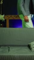 Vertical Fatigued player in RGB lit home late at night gaming with gamepad. Sleepy person sitting on sofa in neon illuminated apartment, playing videogames on console, looking exhausted, camera B video