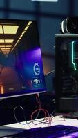 Vertical FPS videogame left open on PC screen in empty neon illuminated apartment living room. Shooter game on computer desktop display in RGB lit home late at night with no people in video