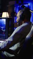 Vertical Player using keyboard, mouse and headset to play first person shooter videogame on PC, enjoying leisure time. Man in living room using high tech computer peripherals to destroy enemies, camera B video