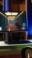 Vertical Stylish empty apartment with neon lights and computer screen left open at night showing videogame UI interface. Home living room with no people in and PC display left open video