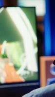 Vertical Man using headset to play SF FPS videogame, having fun in dark apartment room. Gamer competing in PvP online multiplayer game, shooting other players with futuristic gun, camera A close up video