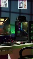 Vertical Professional gaming empty room studio with neon lights and RGB lit powerful computer, first person shooter game left open on screen. FPS videogame on pc display in apartment late at night video