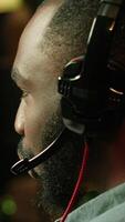 Vertical Close up of pro streamer streaming videogame on powerful computer during online gaming championship, talking into headset. Gamer taking part in Esport team of gamers, competing in game, camera A video