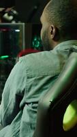 Vertical Man playing SF shooter videogame on computer monitor, talking into headset with friends. Gamer using headphones while enjoying game with spaceship flying to chat with Esports team, camera A video