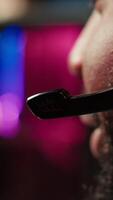 Vertical Close up of headset mic used by professional streamer competing in intense online multiplayer videogame live from home. Focus on headphones microphone used by man playing on gaming PC, camera A video
