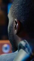 Vertical Man at home plays online multiplayer spaceship videogame with friends, relaxing, close up. African american player, flying spacecraft, enjoying leisure time in RGB lights adorn apartment, camera A video