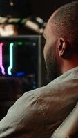 Vertical Gamer in neon lit apartment home shooting meteorites in spaceship flying singleplayer game on computer desktop. Player navigating galaxy, exploding enemies in simulation game on gaming PC, camera A video