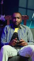 Vertical Gamer upset after losing while playing videogames on console system using controller. Man putting face in hands in frustration after being defeated playing games with gamepad, camera B video