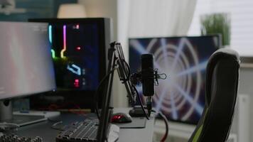Game loading on display of RGB professional powerful computer and stream chat is prepared for virtual tournament. Streaming professsional microphone in empty gaming home studio with neon lights. video