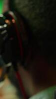 Vertical Man wearing headphones on while playing videogames at home to better immerse himself. Close up of player participating in online multiplayer esports tournament, fighting to defeat enemies, camera A video