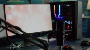 Game is loading on display of RGB professional powerful computer and stream chat is prepared for virtual tournament. Streaming professsional microphone in empty gaming home studio with neon lights. video