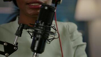 Close up of african influencer answering questions while talking into microphone for listeners. Speaking during livestreaming, blogger discussing in podcast wearing headphones. video