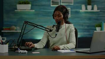 Black blogger woman recording for her blog in home studio reading messages checking sound on mixer. On-air online production internet broadcast show host streaming live content for social media video