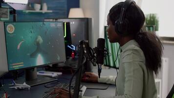 Furious black woman gamer with headphones using stream chat losing game playing on RGB powerful computer shooter game. Virtual online streaming cyber checking sound performing in gaming tournament video