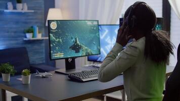 African cyber gamer putting on headset before playing online games using RGB keyboard and mouse. Player performing online games on powerful computer during gaming tournament video