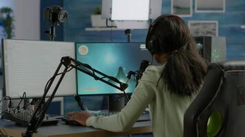 Black player wearing headphones talking with other players chatting while playing professional shooter games in online tournament. Gamer making online videogames with new graphics on powerful computer video