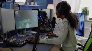 Competitive black gamer with headphones using stream chat on powerful computer winning online shooter game late at night. Virtual online streaming cyber checking sound performing in gaming tournament video