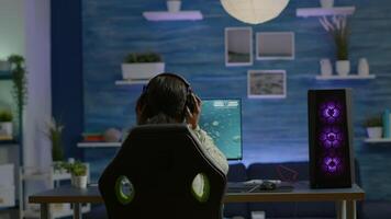 African player sitting on gaming chair with headset playing online space shooter videogames using RGB keyword. Pro cyber streaming online game new graphics using powerful personal computer video