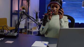 African woman recording vlog and sharing content on streaming platform using social network, checking sound at mixer. Influcencer in digital marketing doing brodcast speaking during livestreaming video