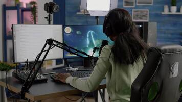 African woman streamer cyber winning performing space shooter game on RGB powerful computer talking with players on stream chat and microphone in gaming competition. Player man streaming video