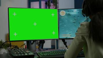 Black woman gamer streaming online videogame on powerful computer with green screen mock up chroma key display. Cyber player using professional pc with isolated desktop playing shooter game in headset video