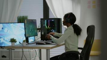 Black woman gamer winning videogames using professional wireless controller and headset playing on powerful computer. Excited online streaming cyber performing during gaming tournament using joystick. video