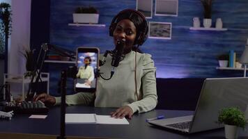 Content creator looking at smartphone camera while talking at mic checking sound during podcast. Online show On-air production internet broadcast host streaming live , recording digital social video
