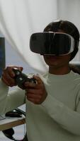 Vertical . Black videogamer woman winning game using virtual reality goggles playing games with modern joypad. Professional gamer streaming online videogames with new graphics on powerful computer video