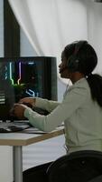 Vertical . Black woman gamer winning videogames using professional wireless controller and headset playing on powerful computer. Excited online streaming cyber performing during gaming tournament using joystick. video
