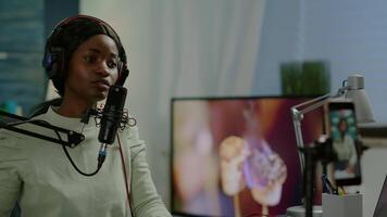 African vlogger recording blog using smartphone with modern equipment in home studio podcast. Media star looking at camera for broadcast and having fun using technology to connect with audiences video