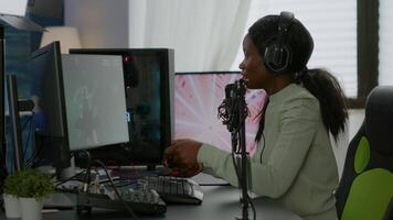 Afro american space shooter player happy after winning virtual competiton using RGB powerful computer. Online streaming cyber performing during games tournament in home with neon lights. video