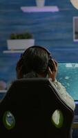 Vertical . African player sitting on gaming chair with headset playing online videogames using RGB keyword. Pro cyber streaming online game new graphics using powerful personal computer video