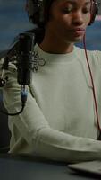 Vertical . Portrait of african smiling blogger looking at camera before starting live from home studio podcast. Content creator vlogger woman recording brodcast streaming online content for social media video