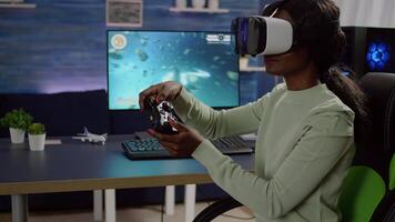 Black woman videogame player with vr goggles raising hands holding joystick after winning space shooter competition. Professional pro cyber playing online game with new graphics on powerful computer video