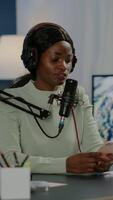 Vertical . African blogger woman reading messages on smartphone recording for her blog in home studio. On-air online production internet broadcast show host streaming live content for social media video