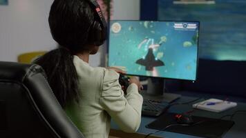 Back shot of pro black woman streamer winning graphics cyber space shooter games using wireless joystick. Gamer performing on powerful pc talking with players on chat open during competition video