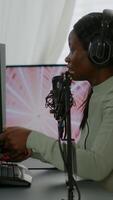 Vertical . Afro american player happy after winning virtual competiton using RGB powerful computer. Online streaming cyber performing during games tournament in home with neon lights. video
